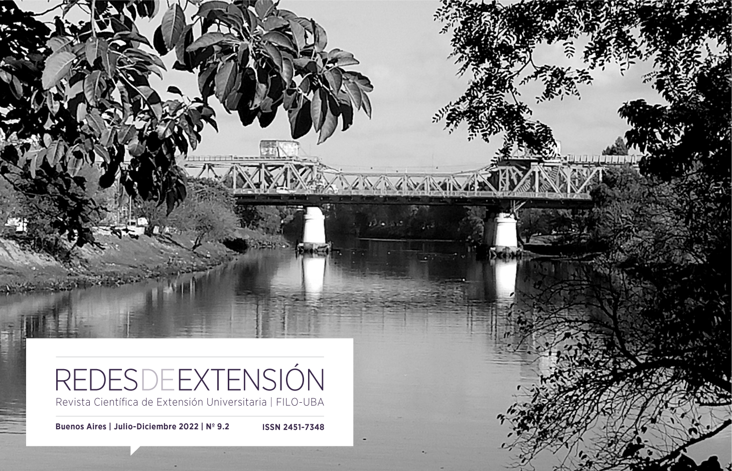 Fotografía en blanco y negro, dos mujeres caminan detrás una inmensa pared fabril