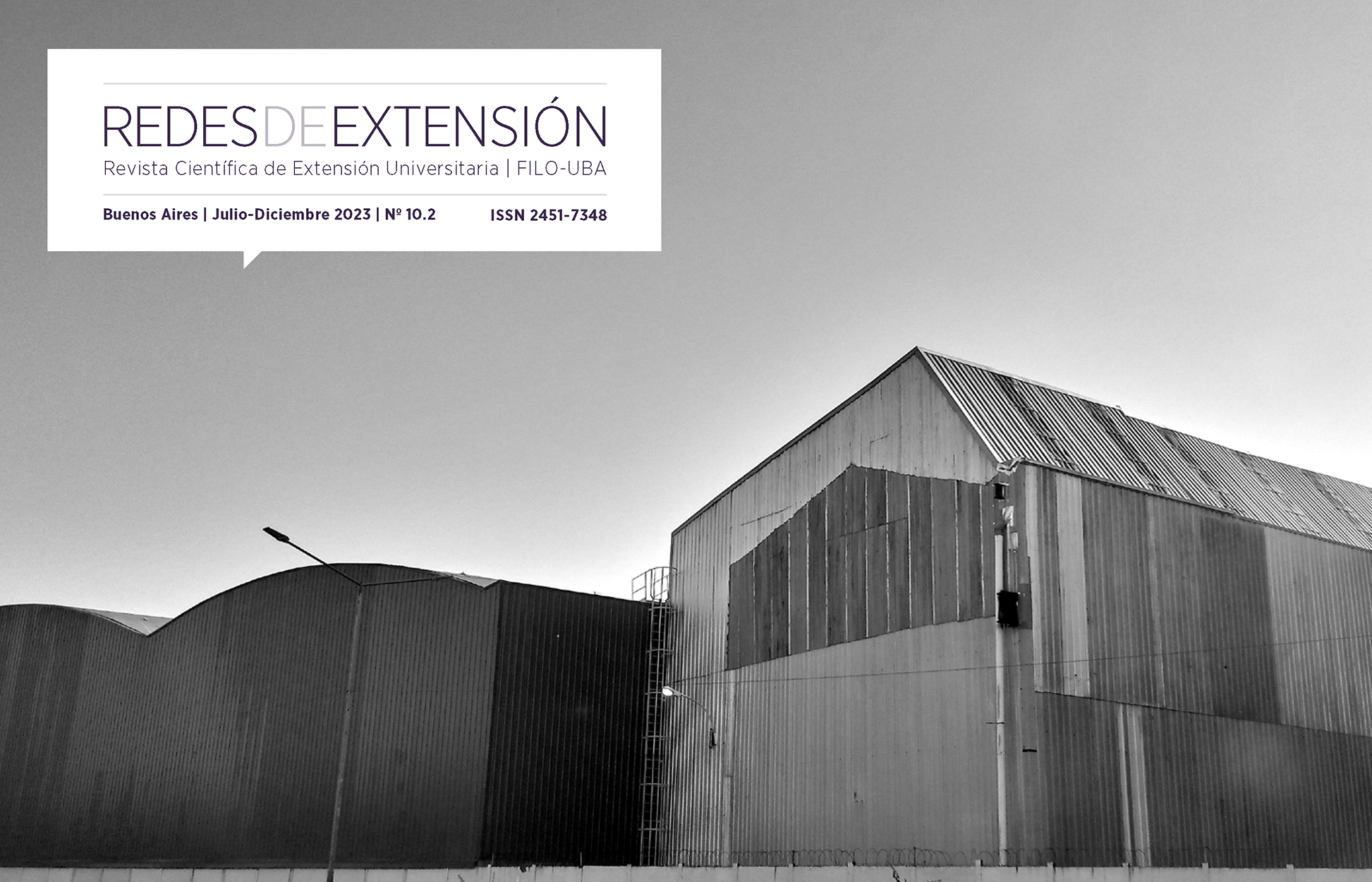 "Paisaje fabril". Fotografía en blanco y negro sur de CABA, Pompeya. Se imponen enormes galpones de chapa y el contorno de sus techos forman una línea continua de formas geométricas en el cielo.